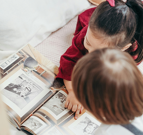 Two children looking through a photo book, exploring memories together.