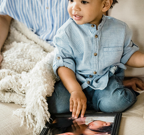 Child sitting down holding a custom frame, featuring a personalized design ready for display.