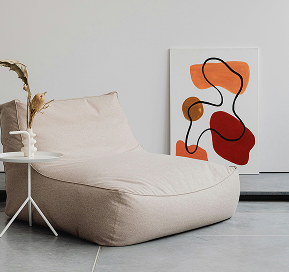 Comfy, artsy chair positioned in front of displayed art prints, creating a stylish and creative interior setting.