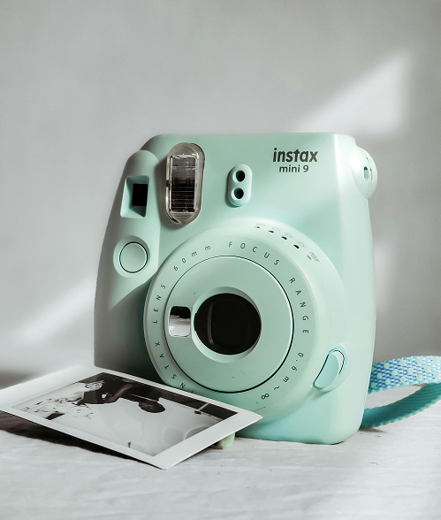 Mint-colored Instax Mini 9 camera with a printed photo placed in front, highlighting instant photography.